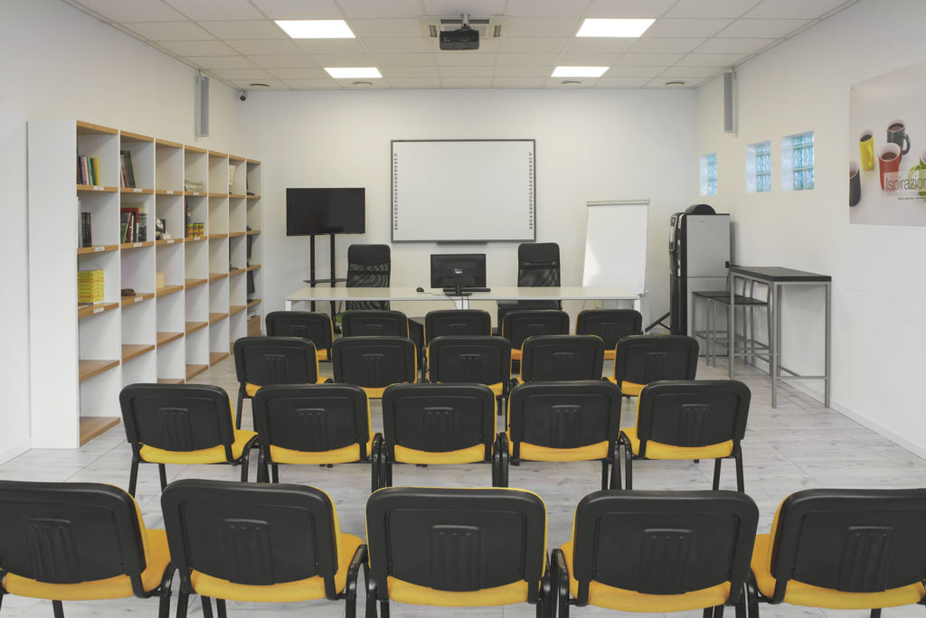 Sala Riunioni allestita per una conferenza con sedie allineate che guardano la lavagna ed il televisore